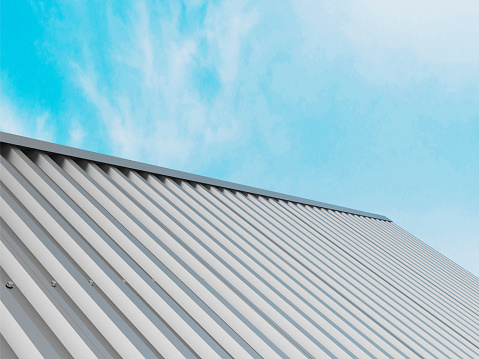 Roof shingles on top of the house against blue sky with cloud, dark asphalt tiles on the roof background