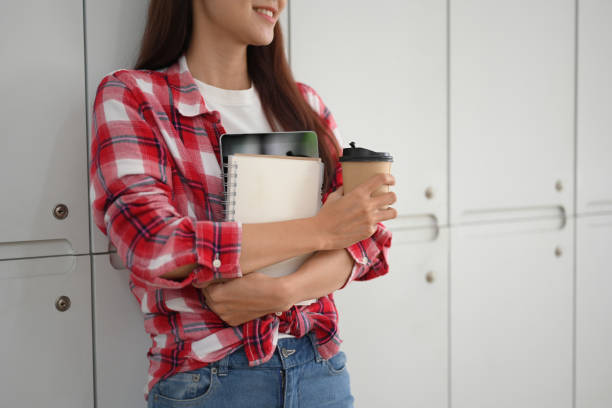 istock Cropped, Attractive asian female university student with her stuff, standing in locker room. 1404804482