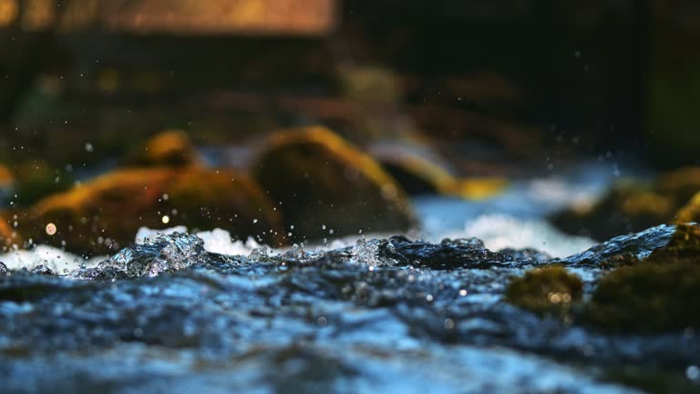Time warp super slow motion shot of droplets splashes up in the air from rapids of a spring water flows down the riverbed.