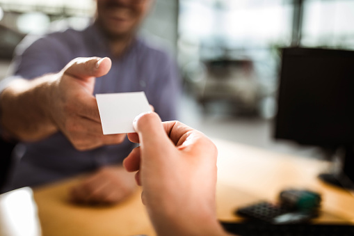 Close up of unrecognizable agent giving her business card to customer. Copy space.