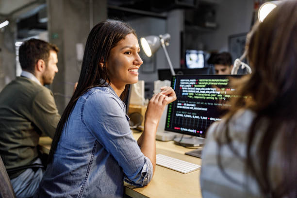 istock Happy female programmer talking to her colleague in the office. 1404809493