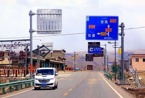 National Highway 317 runs east-west, connecting northern Tibet with Sichuan province. The road sign says: Forward (East) is Ganzi County, turn left is Shiqu County. Photo in May 2021, Ganzi County, western Sichuan. The location was about 4,180 m asl.