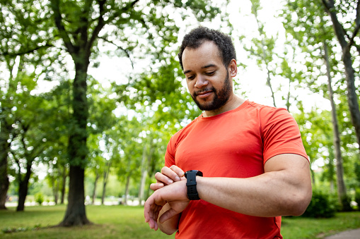 Young man jogging in the park. Measuring pulse