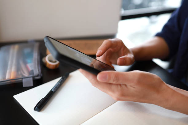 istock Close-up of woman using smartphone at desk 1404811061