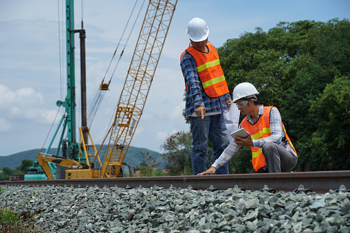 2 asian engineers working outside for checking the build a high-speed railway.
