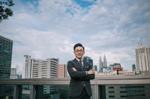 Asian Chinese successful businessman looking at camera smiling with cityscape background