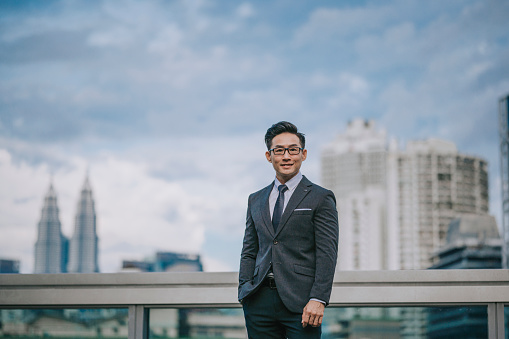 Asian Chinese successful businessman looking at camera smiling with cityscape background