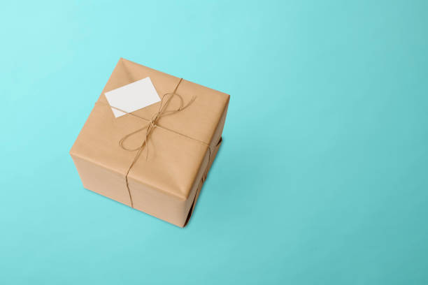 istock Parcel wrapped in brown paper with a blank label on light blue background 1404812531