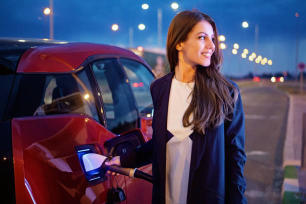 Portrait of young woman charging her electric car stock photo