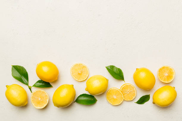 istock Many fresh ripe lemons with green leaves on colored background, top view, space for text 1404814679