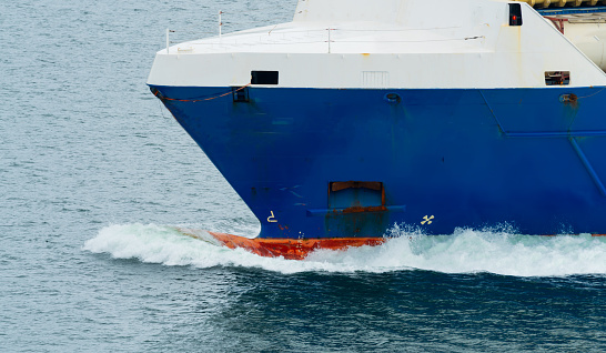 Bulbous bow on a large Cargo ship moving through the water at sea. Close up.