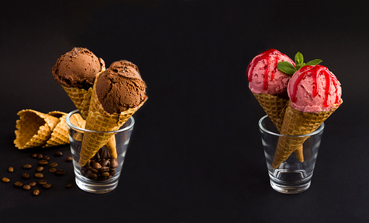Banner. Close-up on chocolate and strawberry ice cream and in the waffle cone on the black background. Copy space.