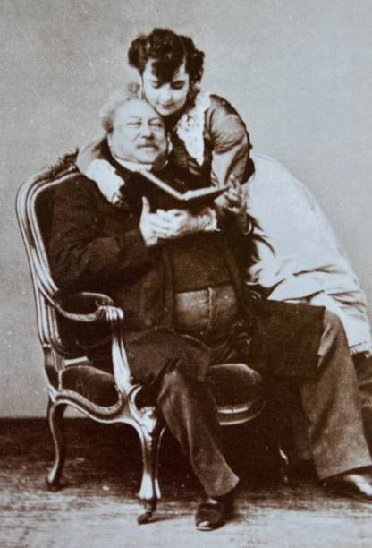 istock Sitting Alexandre Dumas, holding an open book, his female friend standing behind him, Miss Menken, 1867 1404820768