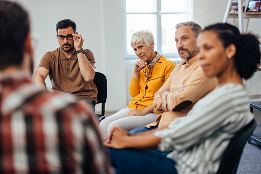 Concentrated people, listening carefully to others from the group therapy.