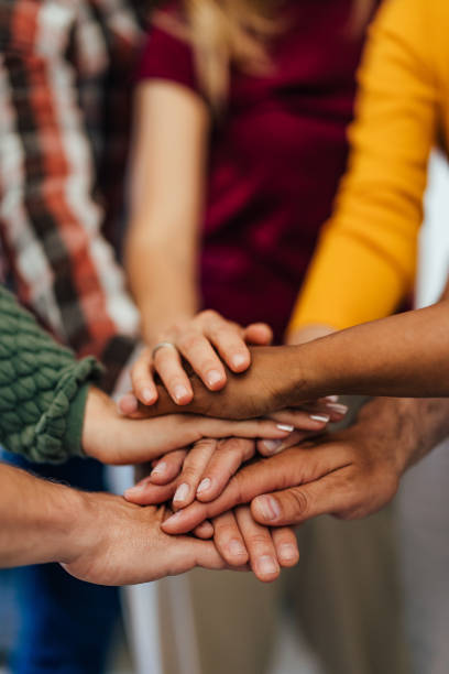 istock All aged people holding hands one over the other, looking supportive. 1404822443