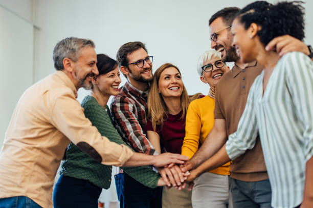 A group of smiling people finished a therapy session, putting hands in the middle. stock photo