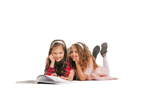 Reading books. Happy smiling girls, kids in retro style outfit, fashion of 70s, 80s years isolated on white background. Concept of emotions, facial expression, beauty. Copy space for ad