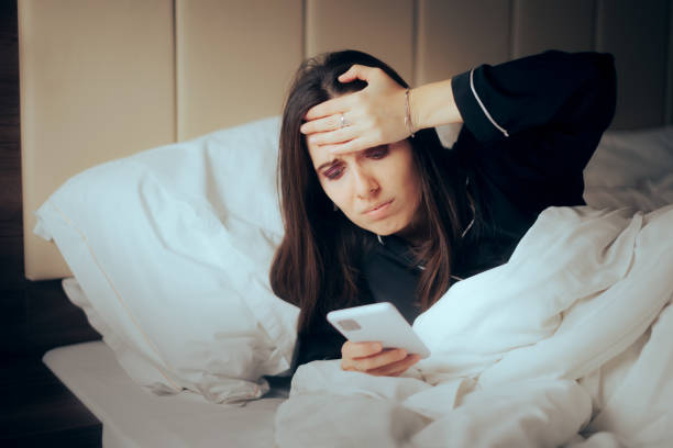 istock Stressed Woman Checking her phone in Bed during Nighttime 1404824336
