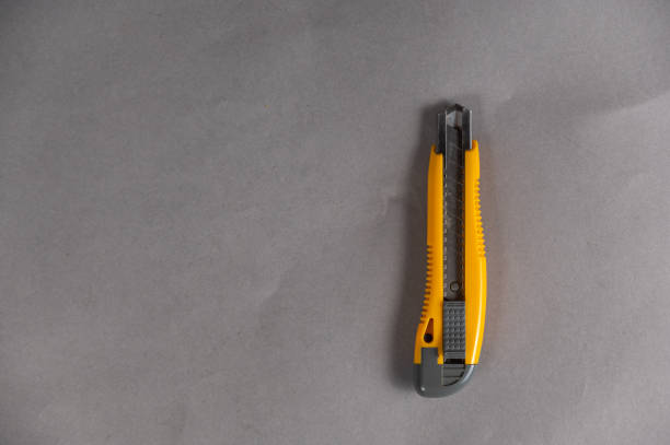istock Yellow paper cutter lies on an uneven gray surface. Hand tool. Top view. Copy space for text and design elements. 1404825746