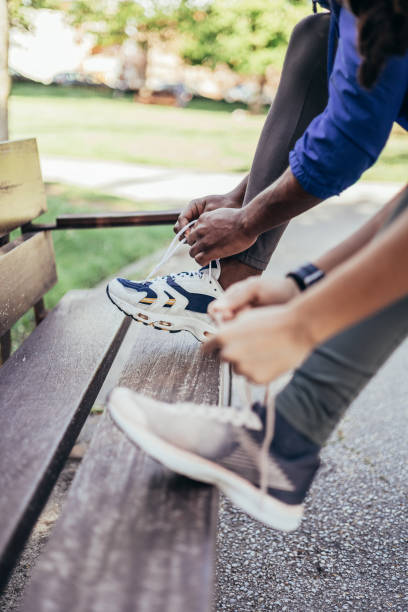 primo piano di irriconoscibili amici latini che legano scarpe da ginnastica. concetto di scarpe sportive. - sports footwear foto e immagini stock