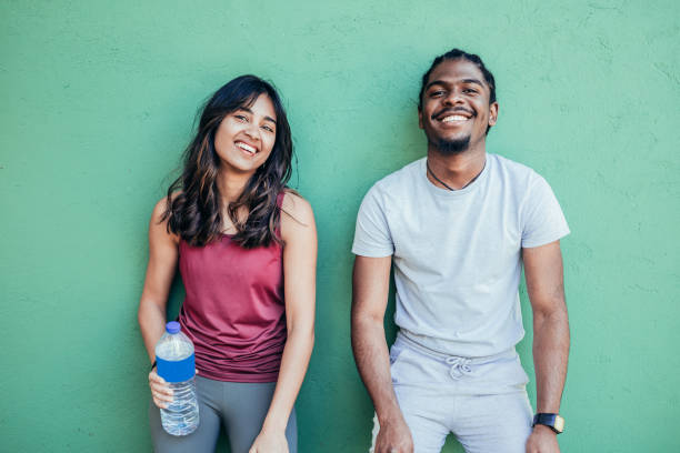 istock Two athletes resting after hard street workout session leaning on a stone wall. African american man and indian woman resting and drinking water 1404827484