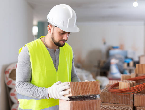istock Young builder inspects and stacks bricks on top of each other 1404827596