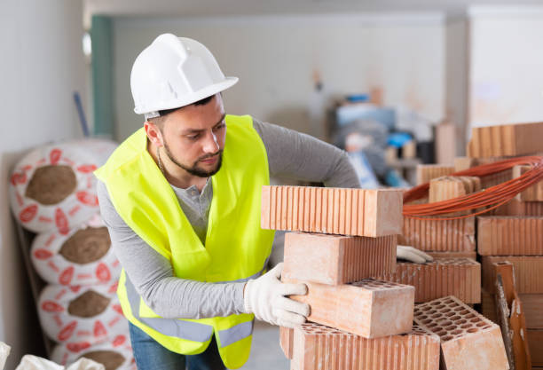 istock Young builder inspects and stacks bricks on top of each other 1404827610