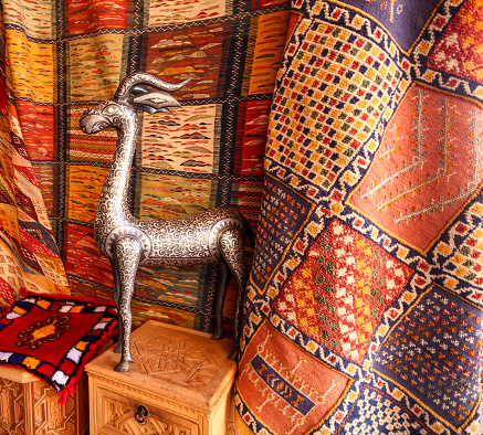 Fez, Morocco-September 22, 2013: A metal deer figurine in front of traditional patterned rugs at a market in Fez.