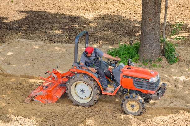 A farmer on a mini tractor loosens the soil for the lawn. Land cultivation, surface leveling A farmer on a mini tractor loosens the soil for the lawn. Land cultivation, surface leveling. garden tractor stock pictures, royalty-free photos & images