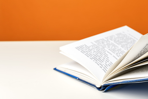Vivid color, open book on a white table against color background.