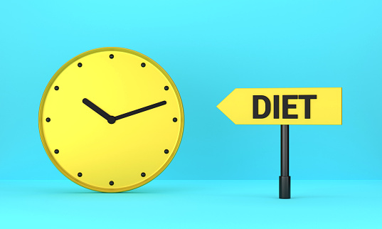 Yellow clock and Diet signpost on blue background. Reminder Concept.