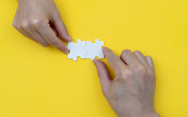 istock Two people put jigsaw puzzle pieces together 1404838941