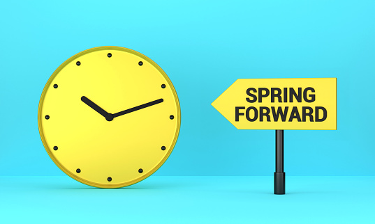 Yellow clock and Spring Forward signpost on blue background. Reminder Concept.