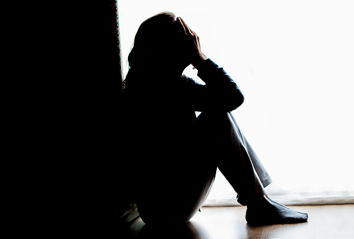 Young woman sitting at the bed and looking through the window