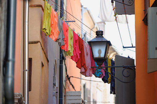 Low angle view on clothes line between houses in Rovinj and old-fashioned street light lantern attached to a wall