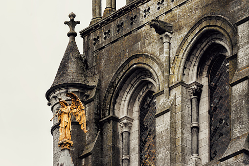 Cork, Ireland - July 26, 2019: St. Fin Barre's Cathedral and detail of the Resurrection Angel. Saint Fin Barre's Cathedral is a Gothic Revival three-spire Church in the city of Cork. It is dedicated to Finbarr of Cork, patron saint of the city. The gilded copper \