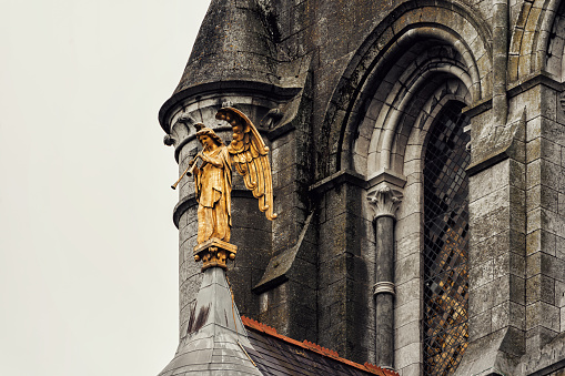 Cork, Ireland - July 26, 2019: Detail of the copper Resurrection Angel of St. Fin Barre's Cathedral. It is a Gothic Revival three-spire Church in the city of Cork. It is dedicated to Finbarr of Cork, patron saint of the city. The gilded copper \