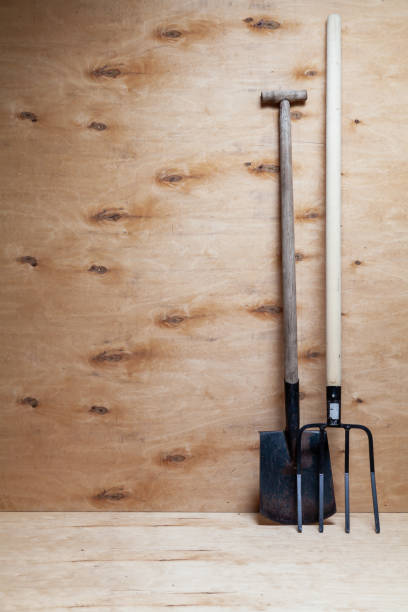 istock Fork on wooden handle and shovel stand on wooden background 1404844825