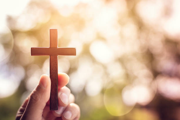 istock Holding religious cross crucifix outdoors with sunset background 1404844846