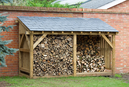 Wood shed, large log store filled with firewood, timber construction with a slate roof, UK