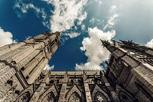 Cobh, Ireland - July 29, 2019: Low point of view of the Cathedral Church of Saint Colman. The Cathedral Church of St. Colman, usually known as Cobh Cathedral, is a single-spire cathedral in Cobh, Ireland. It is a Roman Catholic cathedral and was completed in 1919. It is dedicated to Colmán of Cloyne, patron saint of the Diocese of Cloyne. It serves as the cathedral church of the Diocese. It is one of the tallest buildings in Ireland, standing at 91.4 metres (300 ft).