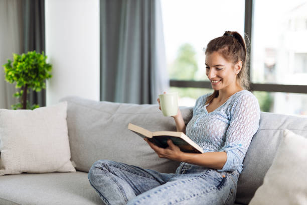istock Relaxed woman reading a book on sofa 1404847338