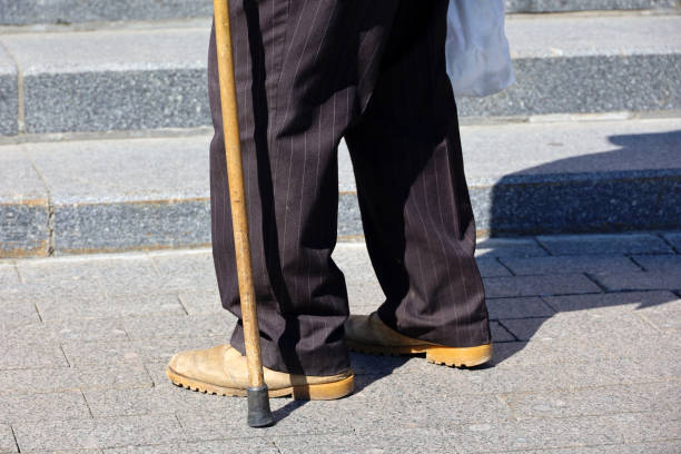 istock Old man with walking cane walking on the street 1404848157