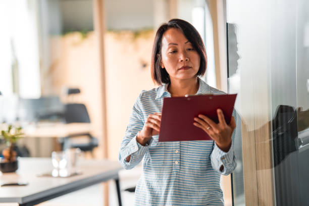 istock Serious Mature Chinese Woman Reading Documents At Work 1404848349