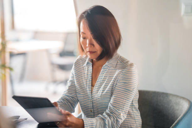 istock Mature Asian Businesswoman Using Technology At Work 1404848363