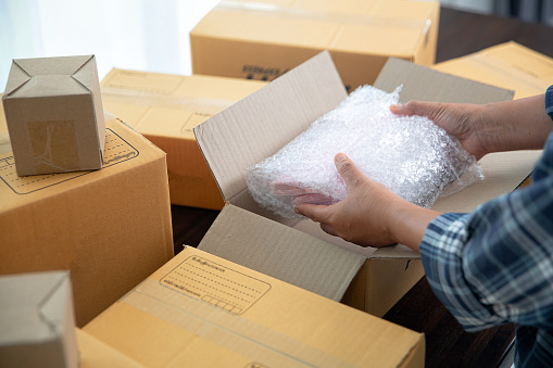 Closeup view of female online store small business owner seller entrepreneur packing package post shipping box preparing delivery parcel.