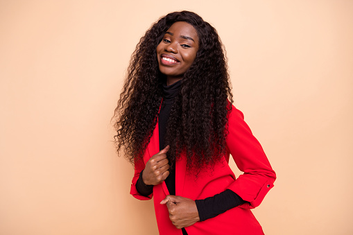 Photo of gorgeous cheerful afro american lady wear red jacket smile good mood isolated on beige color background.
