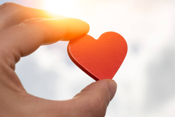 istock Wooden heart holding by hand on sky background 1404850012