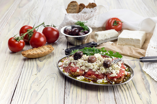 Crackers with grated tomatoes and feta cheese on a wooden table close up (Cretan cuisine)