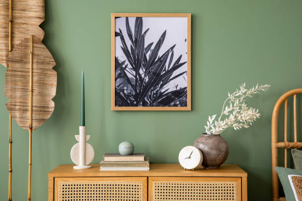 istock Stylish bedroom interior design with mock up poster frame, rattan commode and creative home accessories. Sage green wall. Template. Copy space. 1404851748
